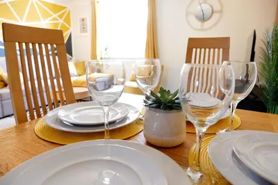 a wooden table with wine glasses and plates on it at Modern 2-Bed Duplex - 10 Mins to City Centre in Chesterton