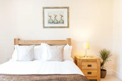 a bedroom with a bed with white sheets and a nightstand at Camstay Longworth Avenue in Cambridge