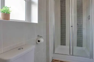 a bathroom with a shower and a toilet paper roll at Elizabeth II Five Bedroom Spacious Home in Bocking Churchstreet