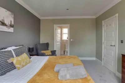 a bedroom with a large bed and a chair at Elizabeth II Five Bedroom Spacious Home in Bocking Churchstreet