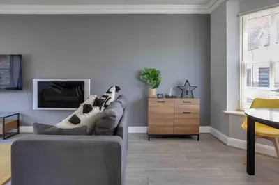 a living room with a gray couch and a table at Elizabeth II Five Bedroom Spacious Home in Bocking Churchstreet