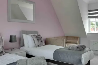 a bedroom with two beds and a chair at Elizabeth II Five Bedroom Spacious Home in Bocking Churchstreet