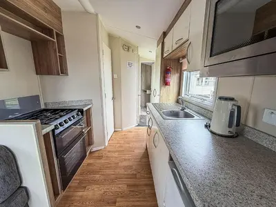 a small kitchen with a sink and a stove at Lovely 6 Berth Caravan At Seawick Holiday Park In Essex Ref 27008S in Clacton-on-Sea