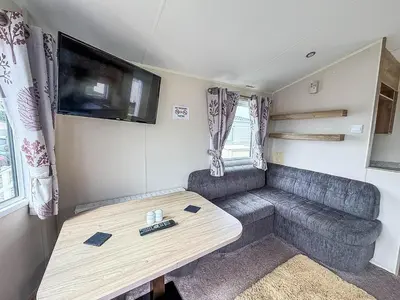 a living room with a couch and a table at Lovely 6 Berth Caravan At Seawick Holiday Park In Essex Ref 27008S in Clacton-on-Sea