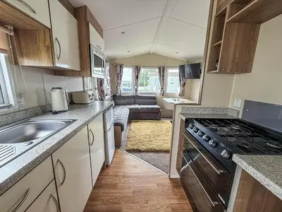 a kitchen with a stove and a living room at Lovely 6 Berth Caravan At Seawick Holiday Park In Essex Ref 27008S in Clacton-on-Sea