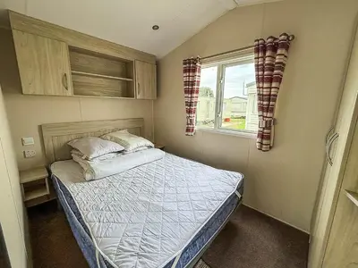 a small bedroom with a bed and a window at Lovely 6 Berth Caravan At Seawick Holiday Park In Essex Ref 27008S in Clacton-on-Sea