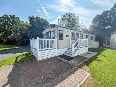 a small white house with a porch and a yard at Beautiful Caravan With Decking At Carlton Meres Holiday Park, Suffolk Ref 60022M in Saxmundham