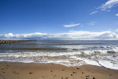 a view of the beach with a pier in the water at Beautiful Caravan With Decking At Carlton Meres Holiday Park, Suffolk Ref 60022M in Saxmundham