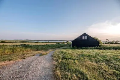 a small house in a field next to a dirt road at Foxglove House, Aldeburgh in Aldeburgh