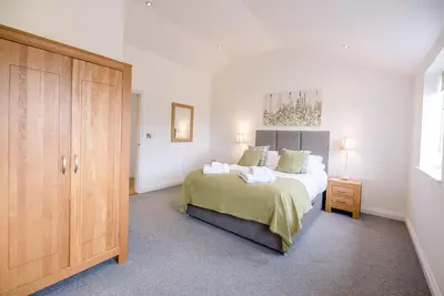 a bedroom with a large bed and a wooden cabinet at Foxglove House, Aldeburgh in Aldeburgh