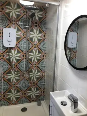 a bathroom with a shower with a mirror and a sink at Sunrise Studio in Colchester