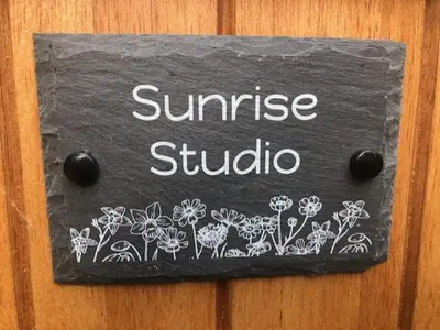 a sign on a wooden door with flowers on it at Sunrise Studio in Colchester