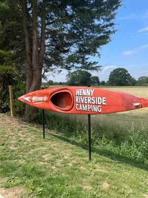 a red kayak on a sign in the grass at Henny Riverside Glamping in Sudbury
