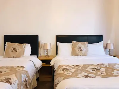 two beds in a room with two lamps on tables at Ilfracombe House Hotel - near Cliffs Pavilion in Southend-on-Sea