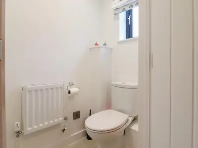 a white bathroom with a toilet and a window at 9 Oaks Court in Leiston