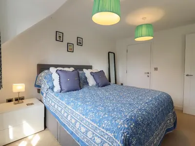 a bedroom with a bed with a blue comforter and two lamps at 9 Oaks Court in Leiston