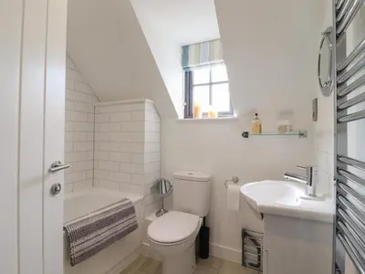 a white bathroom with a toilet and a sink at 9 Oaks Court in Leiston