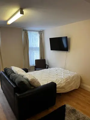 a bedroom with a bed and a couch and a flat screen tv at Entire Apartment boutique king size bed near Town Centre in Colchester