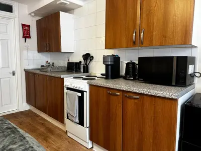 a kitchen with wooden cabinets and a stove top oven at Entire Apartment boutique king size bed near Town Centre in Colchester