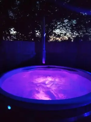 a purple pool of water in a dark room at Bishy Barnabees country lodge with hot tub in Swaffham