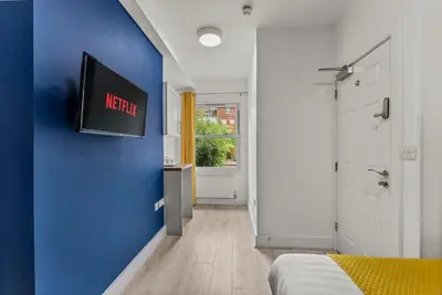 a bedroom with a blue wall and a tv on a wall at The Suffolk Gem - Games Room in Ipswich