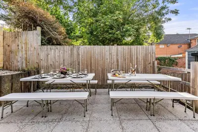 a patio with white tables and a fence at The Suffolk Gem - Games Room in Ipswich