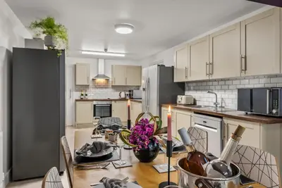 a kitchen with a dining table and a kitchen with white cabinets at The Suffolk Gem - Games Room in Ipswich
