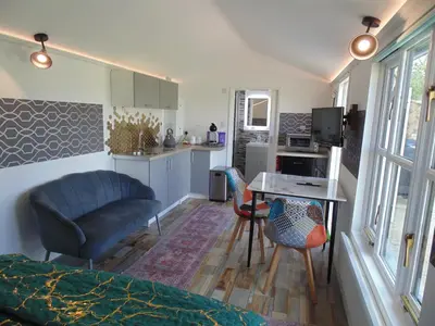 a room with a bed and a table and a kitchen at The Cabin in Pakenham