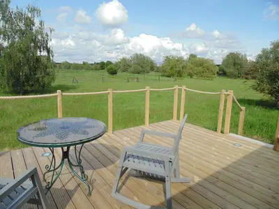 a wooden deck with a table and chairs and a field at The Cabin in Pakenham