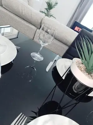 a table with two wine glasses and a plant on it at 2 Bed Apartment with Free Parking in Chelmsford