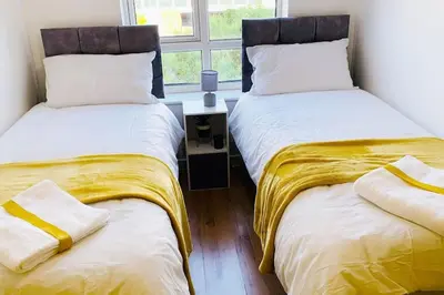two beds sitting next to a window in a room at 2 Bed Apartment with Free Parking in Chelmsford