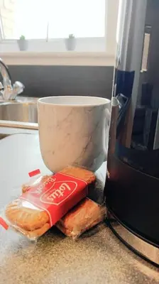a bag of coke on a counter next to a coffee cup at 2 Bed Apartment with Free Parking in Chelmsford
