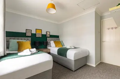 two beds in a room with green and white at Chelmsford Reach 3 bed house near centre,free parking, Wi-Fi, table football in Chelmsford