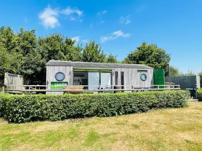 a tiny house in a yard with bushes at Green CargoPod at Lee Wick Farm Cottages & Glamping in Clacton-on-Sea