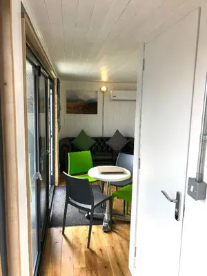 a room with a table and chairs and a couch at Green CargoPod at Lee Wick Farm Cottages & Glamping in Clacton-on-Sea