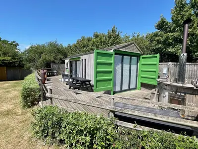 a house with green doors on a wooden deck at Green CargoPod at Lee Wick Farm Cottages & Glamping in Clacton-on-Sea