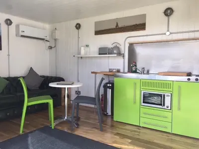 a kitchen with green cabinets and a table and chairs at Green CargoPod at Lee Wick Farm Cottages & Glamping in Clacton-on-Sea