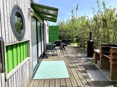 a patio with a table and chairs on a house at Green CargoPod at Lee Wick Farm Cottages & Glamping in Clacton-on-Sea