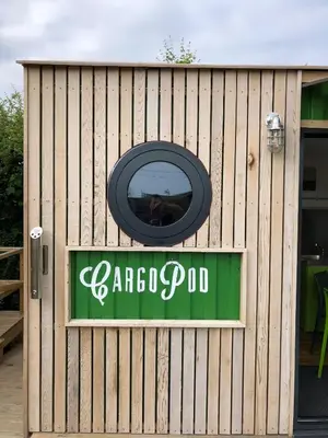 a sign for aarmapod restaurant on a wooden fence at Green CargoPod at Lee Wick Farm Cottages & Glamping in Clacton-on-Sea