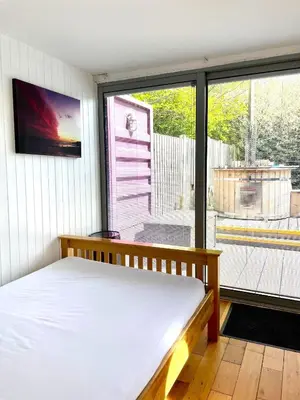 a bedroom with a bed and a large window at Purple CargoPod at Lee Wick Farm Cottages & Glamping in Clacton-on-Sea