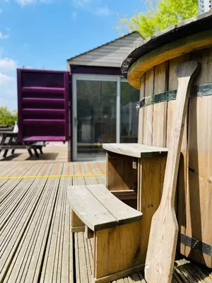 a wooden bench sitting on top of a wooden deck at Purple CargoPod at Lee Wick Farm Cottages & Glamping in Clacton-on-Sea