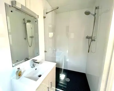 a white bathroom with a sink and a shower at Purple CargoPod at Lee Wick Farm Cottages & Glamping in Clacton-on-Sea