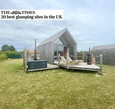 a small shed with a deck in the grass at Lushna 10 Classic Suite at Lee Wick Farm Cottages & Glamping in Clacton-on-Sea