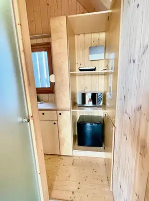 a small kitchen with wooden cabinets and a microwave at Lushna 10 Classic Suite at Lee Wick Farm Cottages & Glamping in Clacton-on-Sea