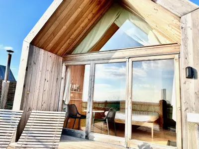 a wooden house with a large glass window at Lushna 10 Classic Suite at Lee Wick Farm Cottages & Glamping in Clacton-on-Sea