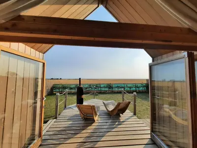 a deck with two chairs and a view of the ocean at Lushna 12 Lux at Lee Wick Farm Cottages & Glamping in Clacton-on-Sea