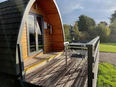 a circular cabin with a deck and a table at MegaPod 3 at Lee Wick Farm Cottages & Glamping in Clacton-on-Sea