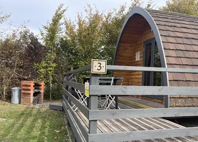 a wooden cabin with a fence in front of it at MegaPod 3 at Lee Wick Farm Cottages & Glamping in Clacton-on-Sea