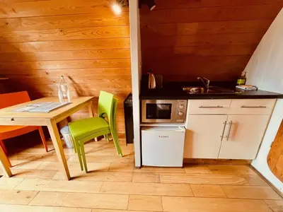 a small kitchen with a table and green chairs at MegaPod 2 at Lee Wick Farm Cottages & Glamping in Clacton-on-Sea