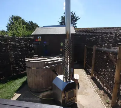 a backyard with a grill and a wooden fence at MegaPod 1 at Lee Wick Farm Cottages & Glamping in Clacton-on-Sea